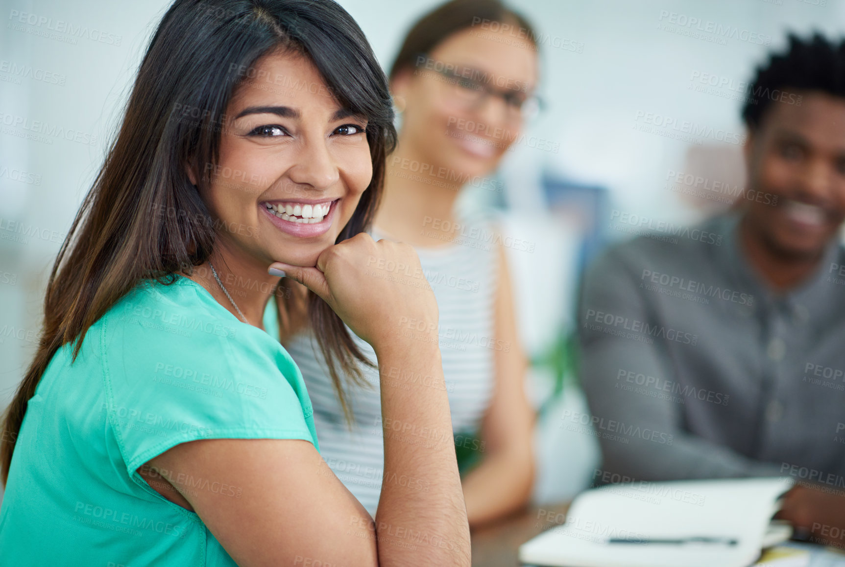 Buy stock photo Portrait of an attractive young woman sitting at a table with colleagues in the background