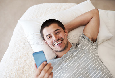 Buy stock photo Bed, phone and a man reading a message at home with chat notification or network for communication. Young person relax with a smartphone and internet connection for chat on mobile app or social media