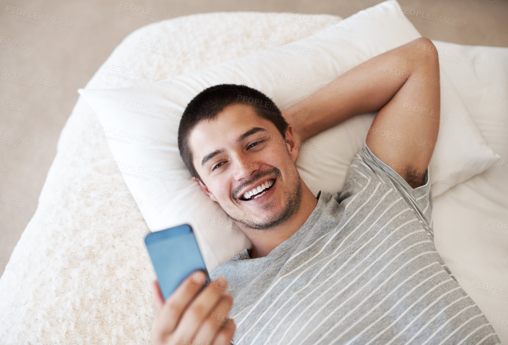 Buy stock photo Bed, phone and a man reading a message at home with chat notification or network for communication. Young person relax with a smartphone and internet connection for chat on mobile app or social media