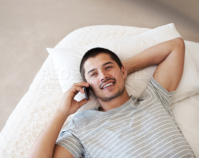 Buy stock photo Phone call, talking and a happy man relax on a bed for a chat, conversation or communication with contact. Casual model person smile and thinking at home with smartphone network and connection