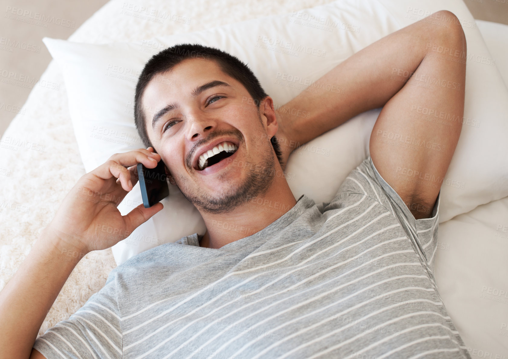 Buy stock photo Happy, man and above with phone call on bed for online, communication and funny conversation. Male person, laughing and relax with tech on pillow at home for network, connection or joke in discussion