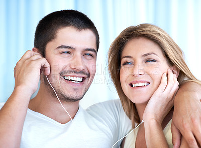 Buy stock photo Attractive young couple listening to music together on some earphones