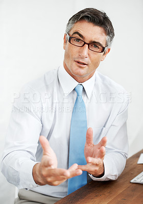 Buy stock photo Handsome mature businessman wearing glasses and explaining something to you 