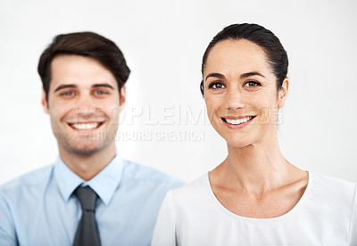 Buy stock photo Two young business colleagues standing together while smiling agianst a white background