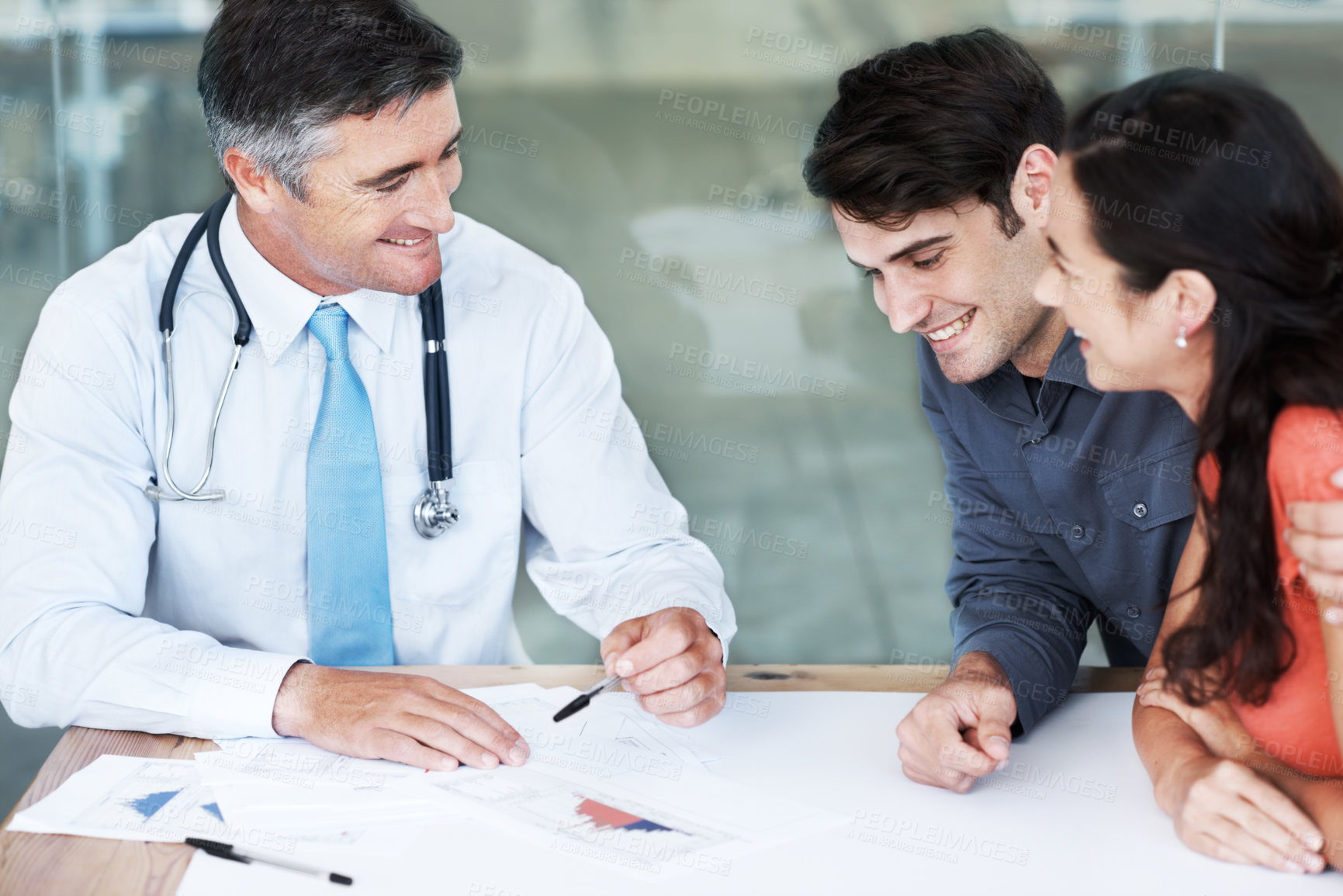 Buy stock photo Hospital, doctor and couple with documents in discussion for health insurance, premium and planning. Man, clients and consultation with paperwork at desk for coverage option, info or medical benefits