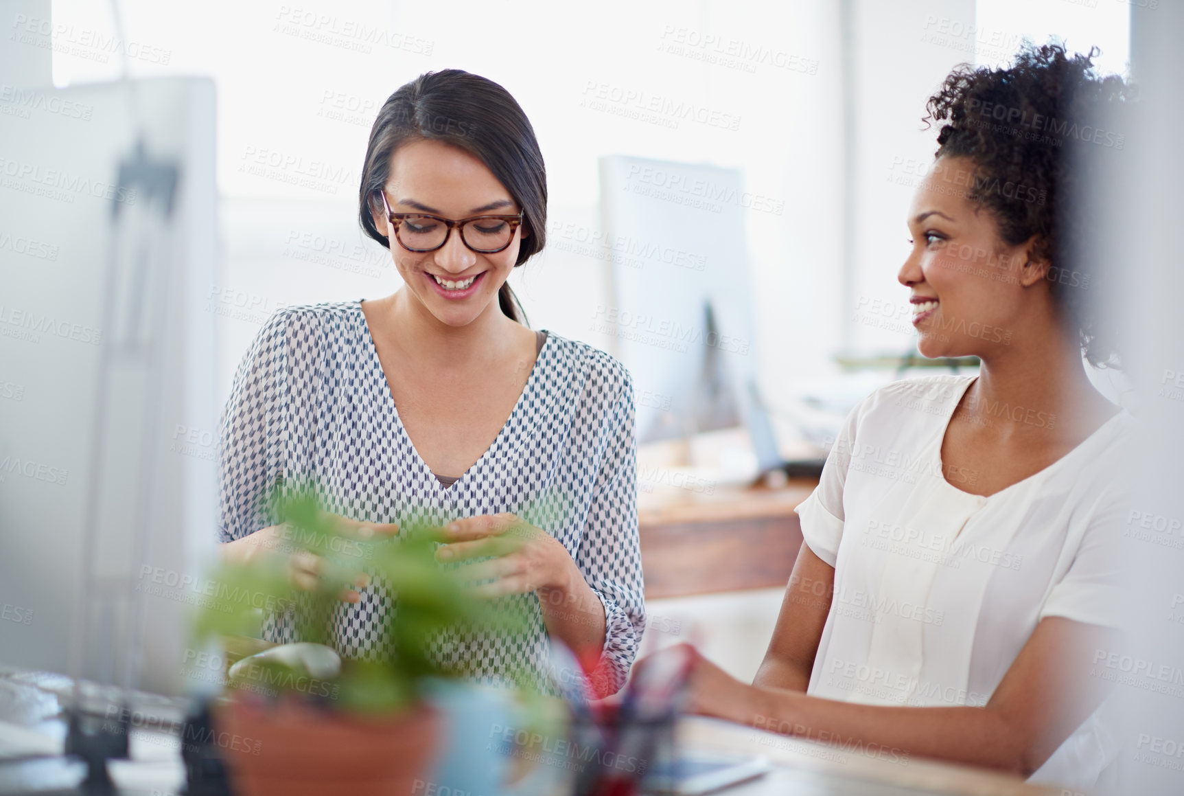 Buy stock photo Shot of two colleagues having a discussion at their desk in the office