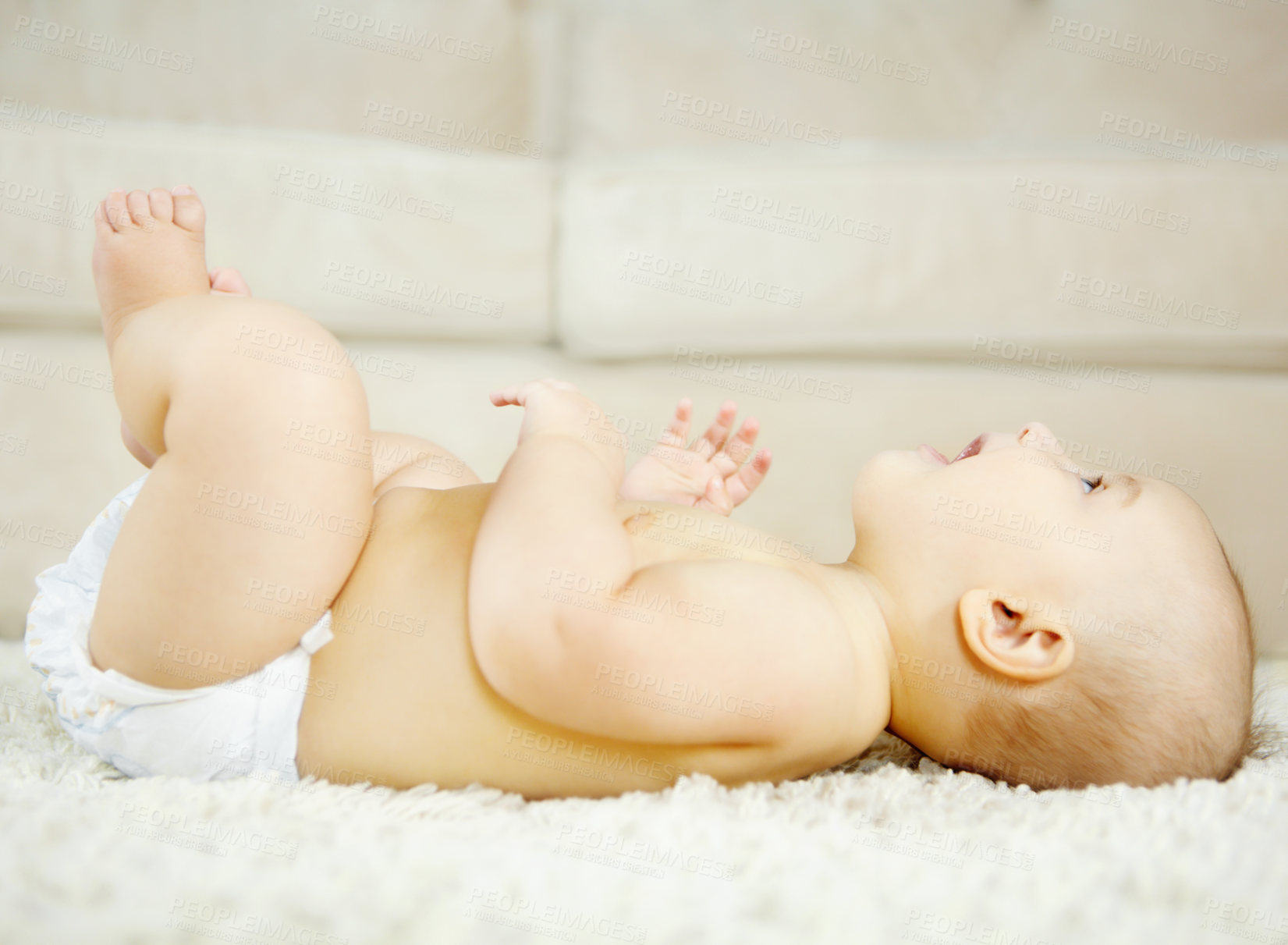 Buy stock photo Cute baby boy lying on the ground and looking around with curiosity and wonder