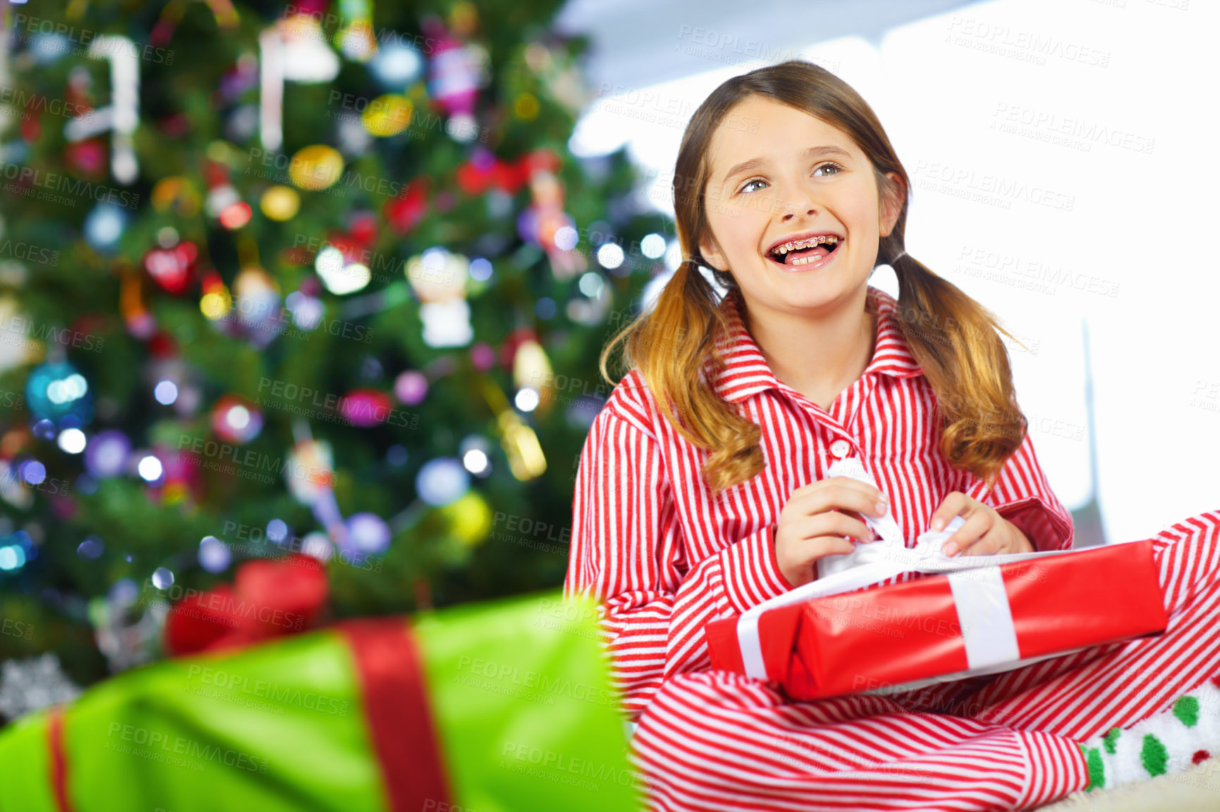 Buy stock photo Cute little girl opening a gift under the tree at Christmas