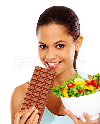 Buy stock photo Portrait of an attractive young woman being tempted to eat a chocolate slab instead of a healthy salad