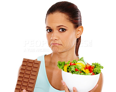 Buy stock photo Portrait of an unhappy young woman choosing between a healthy salad an a chocolate slab
