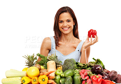 Buy stock photo Attractive young woman smiling while holding a red pepper alongside a pile of fresh vegetables against a white background