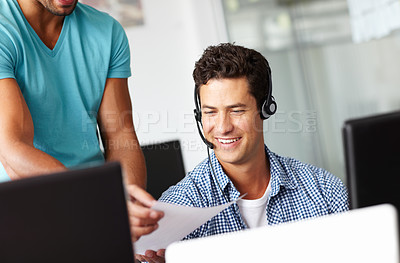 Buy stock photo A handsome young man sitting at his desk and being handed a document