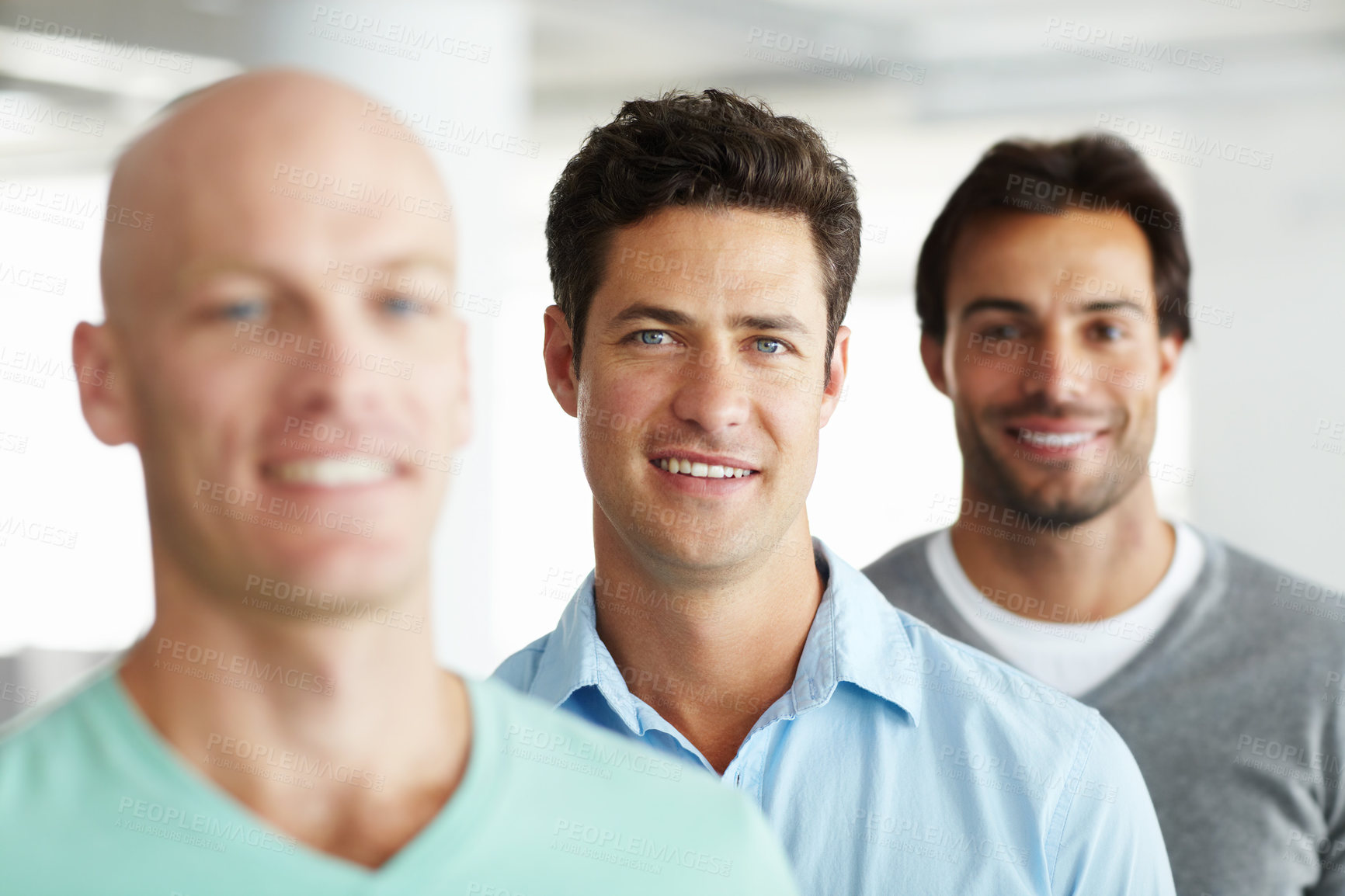 Buy stock photo Shot of a young man standing in an office with male colleagues in the background