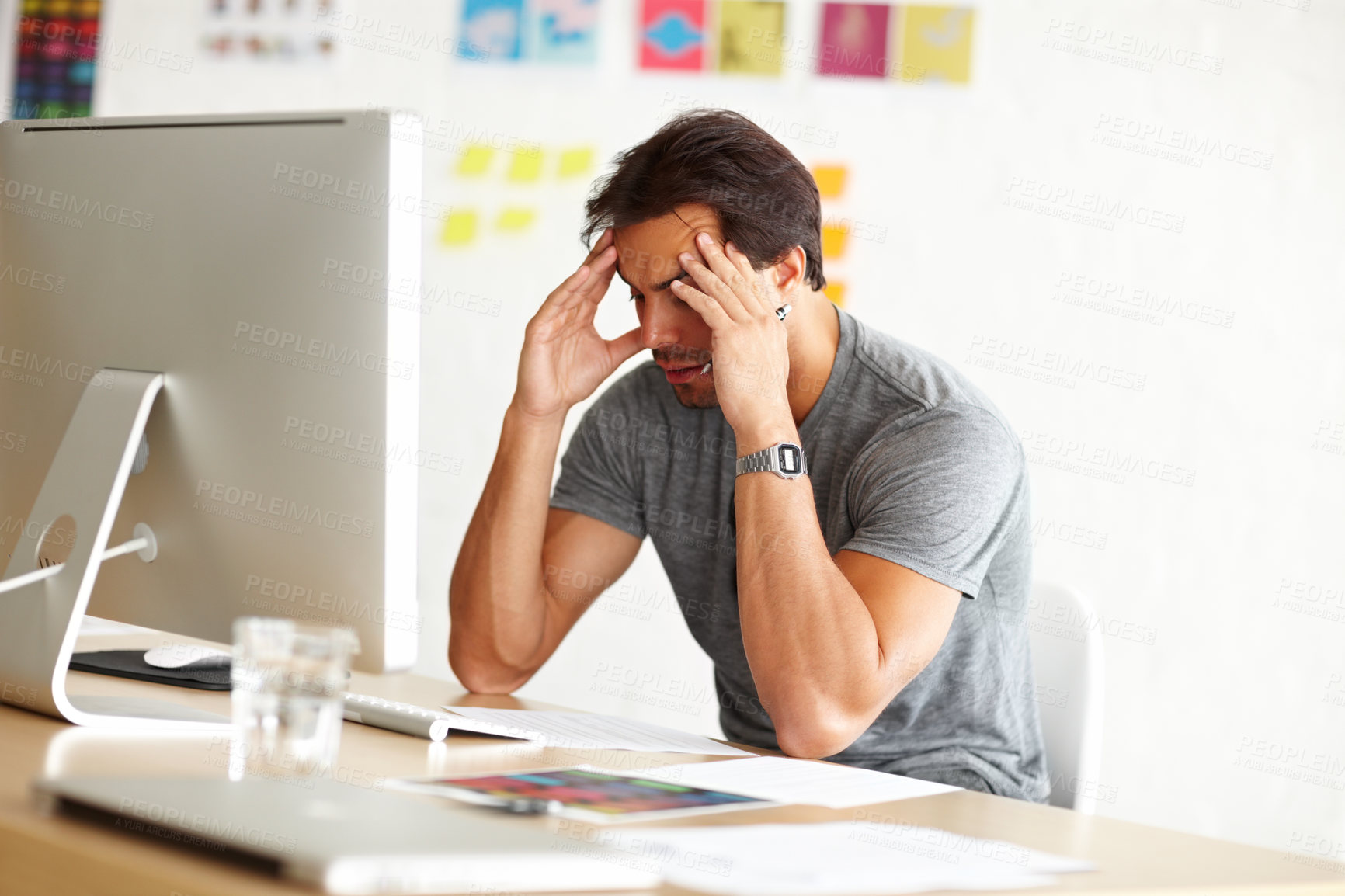 Buy stock photo An overwhelmed man sitting at an office desk with his head rested against hands