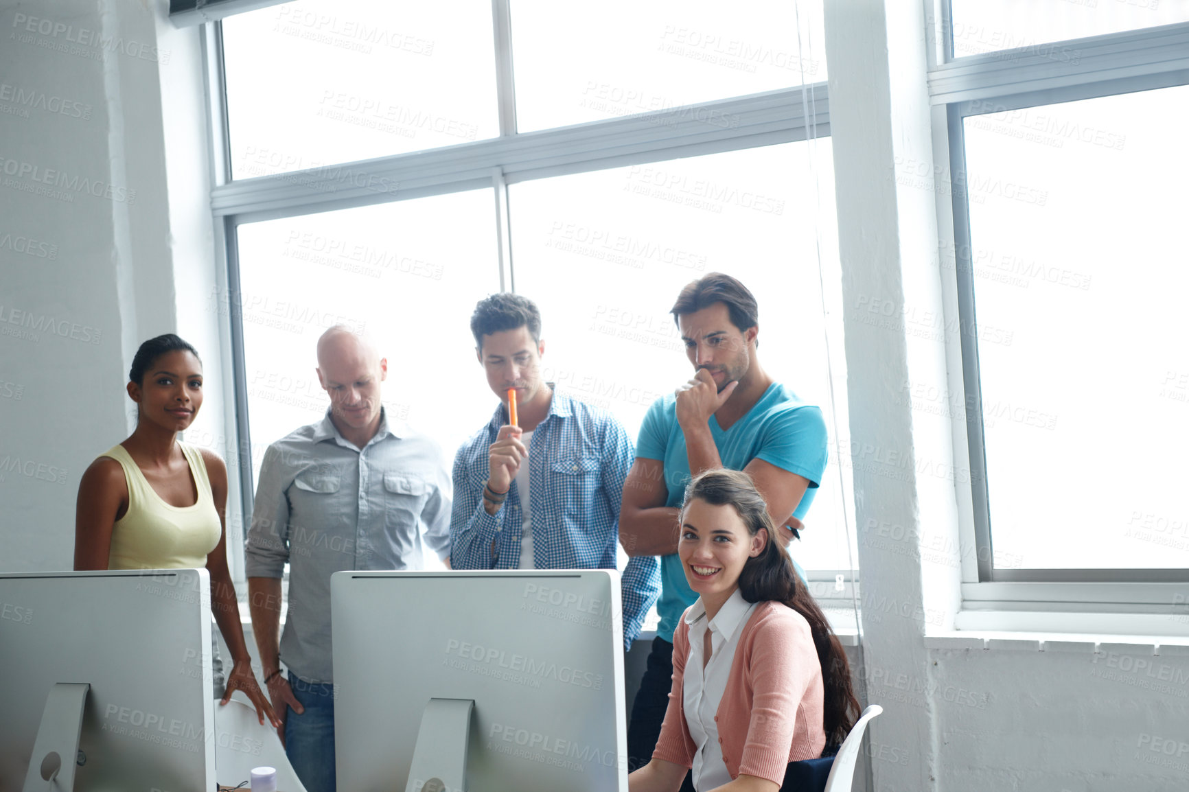 Buy stock photo A group of designers standing in a office together around a computer screen to run over their plans