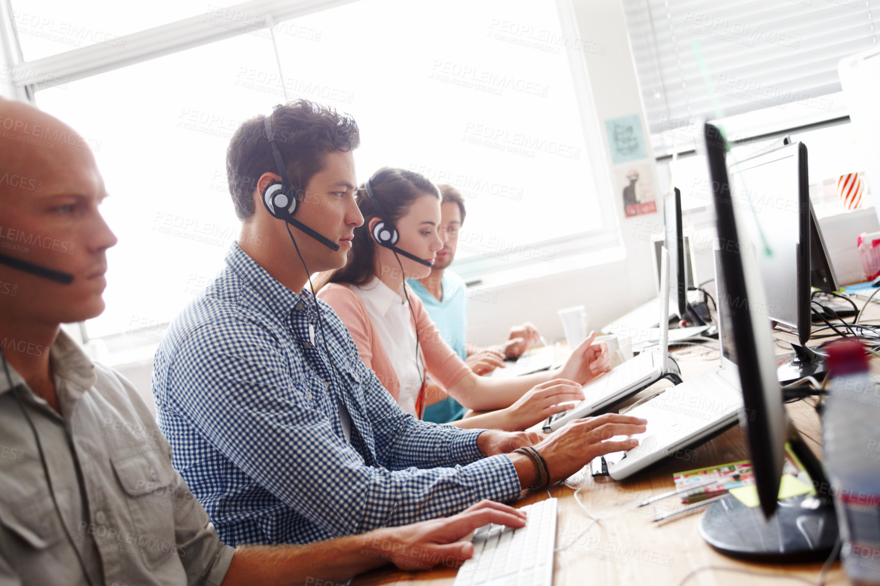 Buy stock photo Sales assistants at the office working in front of their computers wearing headsets
