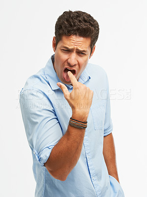 Buy stock photo A young man sticking his finger down his throat in disgust against a white background