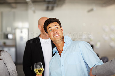 Buy stock photo A drunk man holding a glass of wine and pulling faces at an office social 