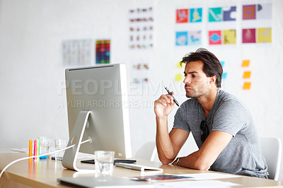 Buy stock photo A handsome young man looking bored in front of his computer
