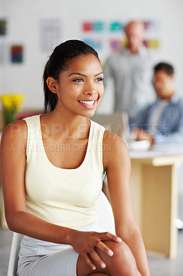 Buy stock photo Shot of a confident young african american designer with her colleagues in the distance behind her