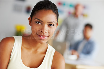Buy stock photo Portrait of a confident-looking young woman with colleagues working in the background