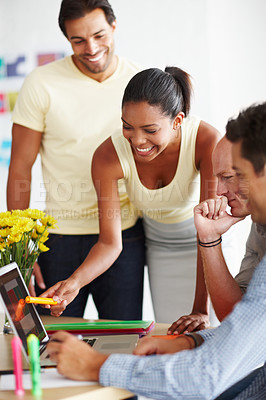 Buy stock photo Shot of a diverse group of coworkers discussing a project over a laptop