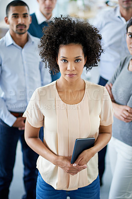 Buy stock photo Portrait of a smiling young office worker standing in an office with colleagues in the background