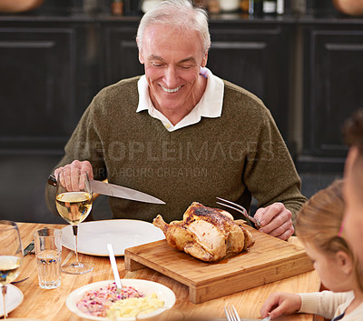 Buy stock photo Shot of a senior man enjoying some roast chicken at the dinner table