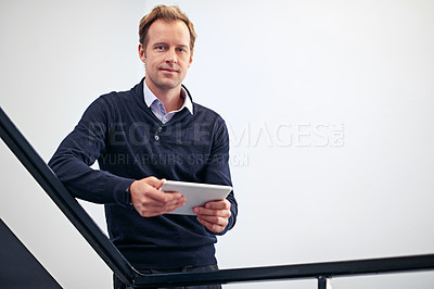 Buy stock photo Shot of a handsome businessman using a digital tablet while standing in a stairwell