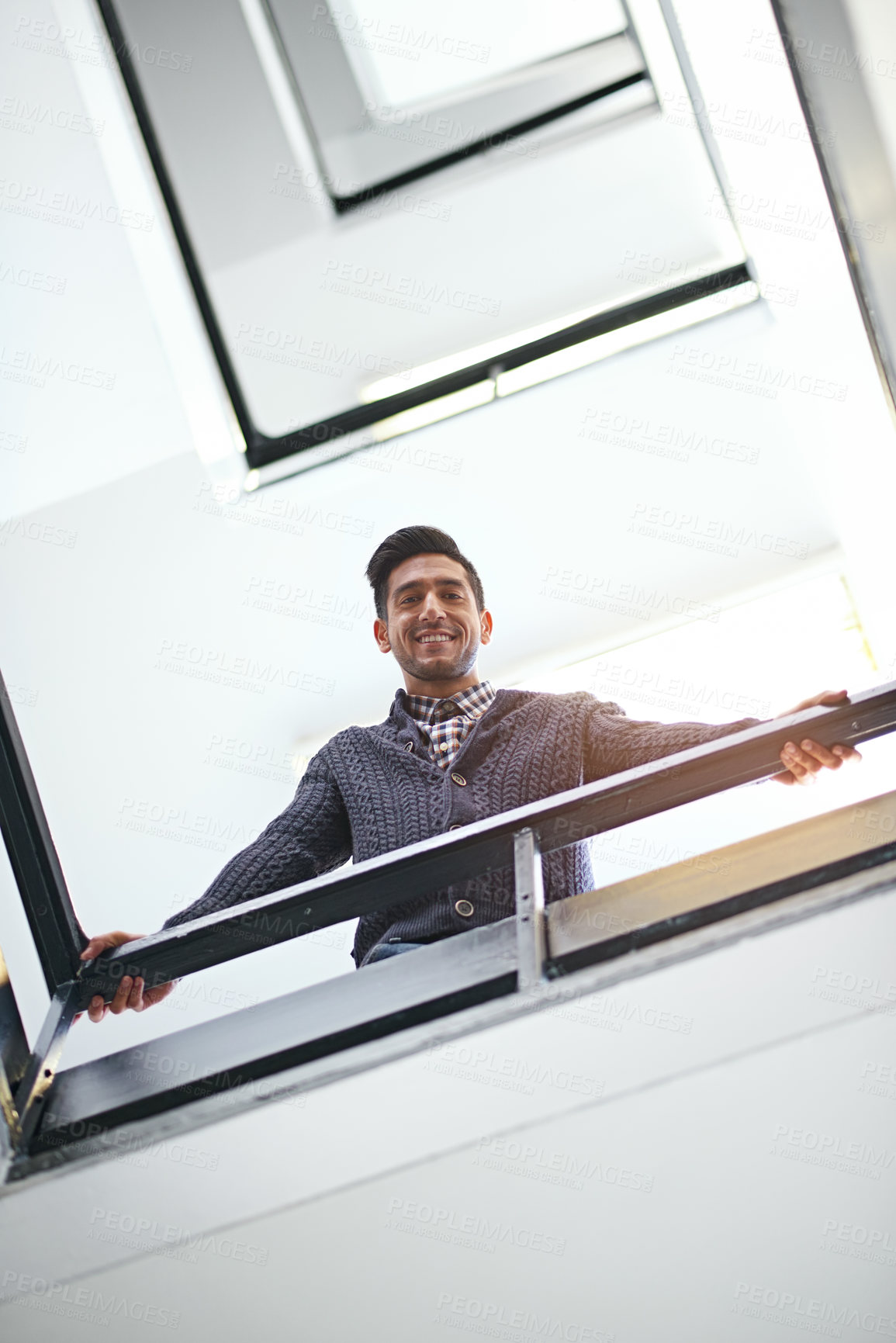 Buy stock photo Low angle portrait of a young businessman leaning on a stairwell bannister