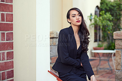 Buy stock photo Shot of a woman wearing a classic feminine suit leaning against an architectural feature