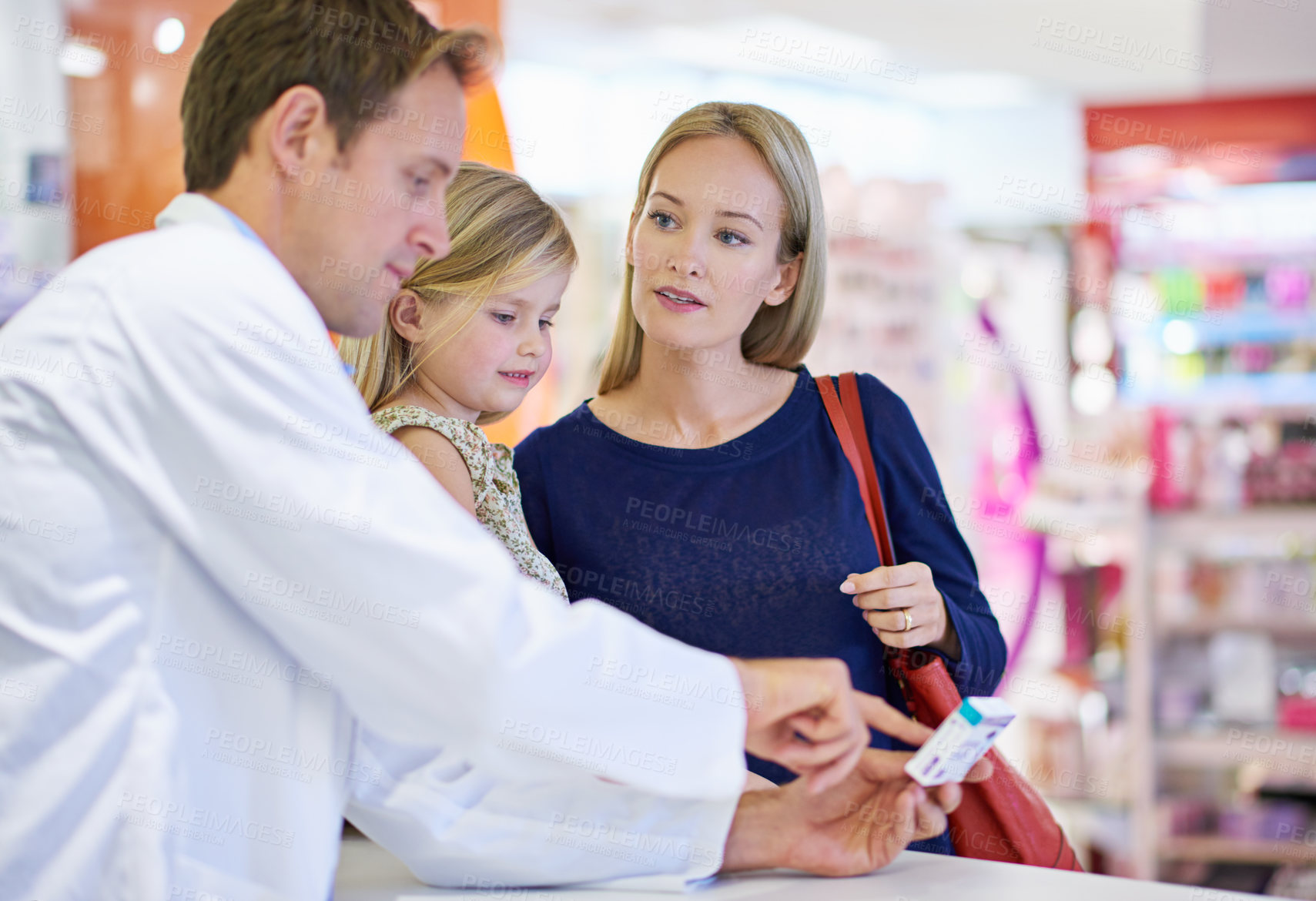 Buy stock photo A pharmacist giving medication to a mother and daughter