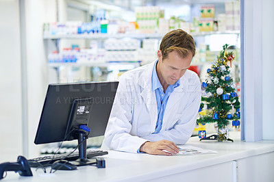 Buy stock photo A pharmacist reading something on his counter