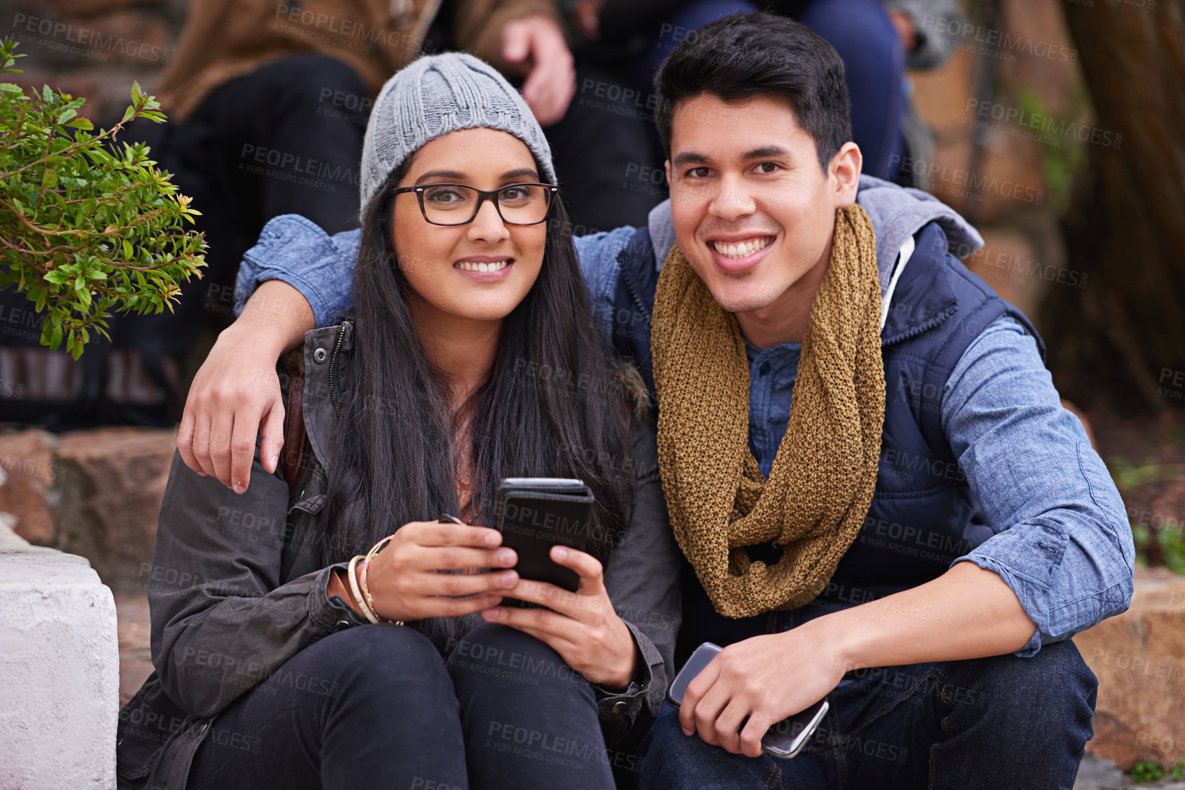 Buy stock photo Students, couple and portrait on campus with smile, smartphones and happiness at college. Man, woman and hug at university for bonding, support and care together and sit on steps on school grounds