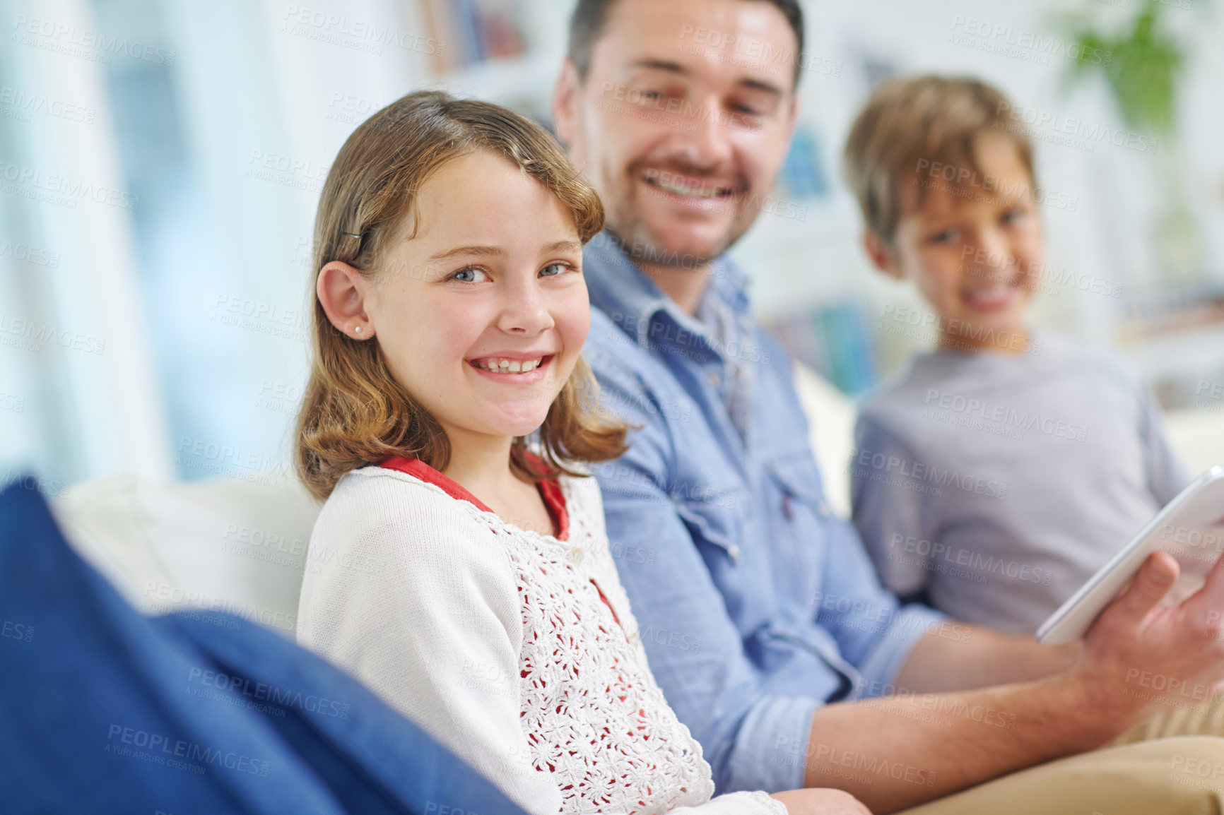 Buy stock photo Portrait of an adorable little girl sitting next to her brother and father while they use a digital tablet together 