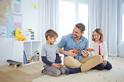 Buy stock photo Shot of a happy father playing the guitar for his son and daughter at home