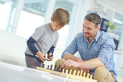 Buy stock photo Shot of an adorable little boy playing a game of chess with his father at home