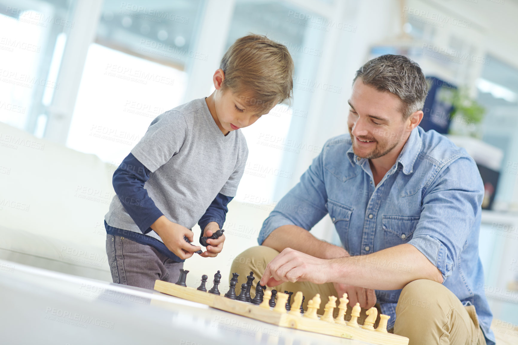 Buy stock photo Shot of an adorable little boy playing a game of chess with his father at home