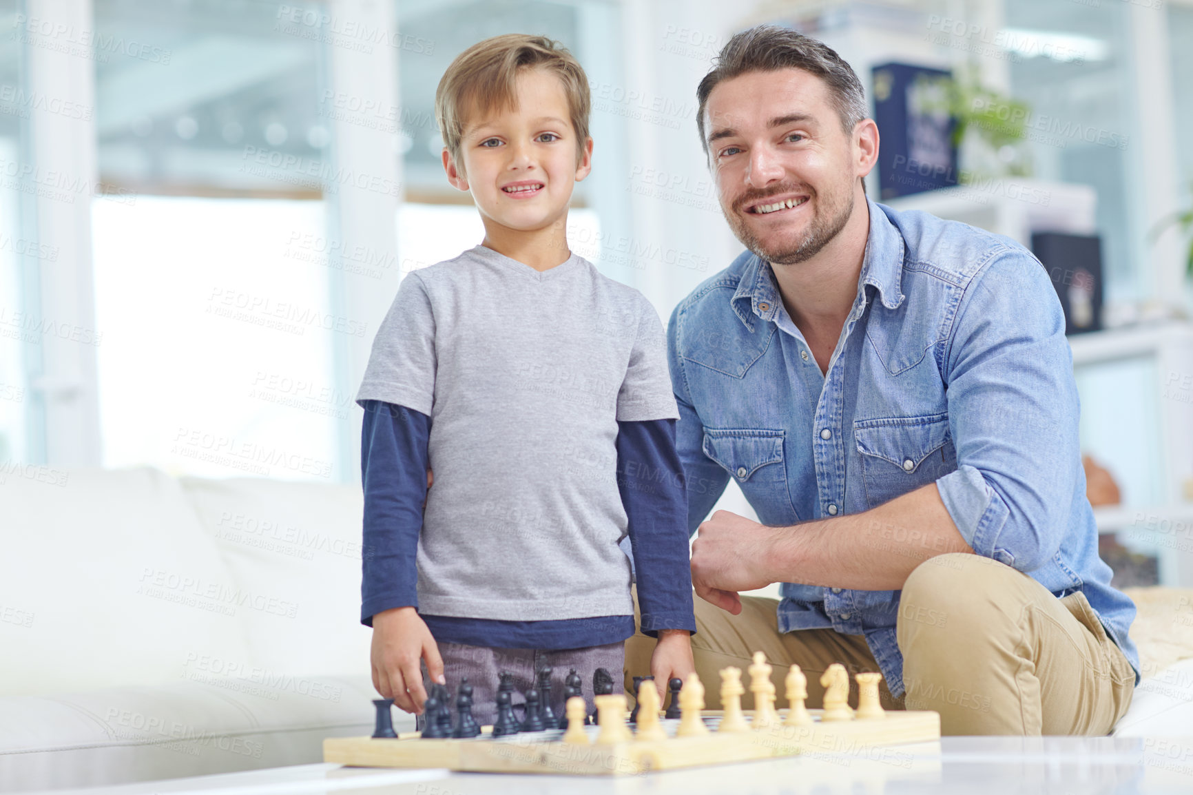 Buy stock photo Shot of an adorable little boy playing a game of chess with his father at home