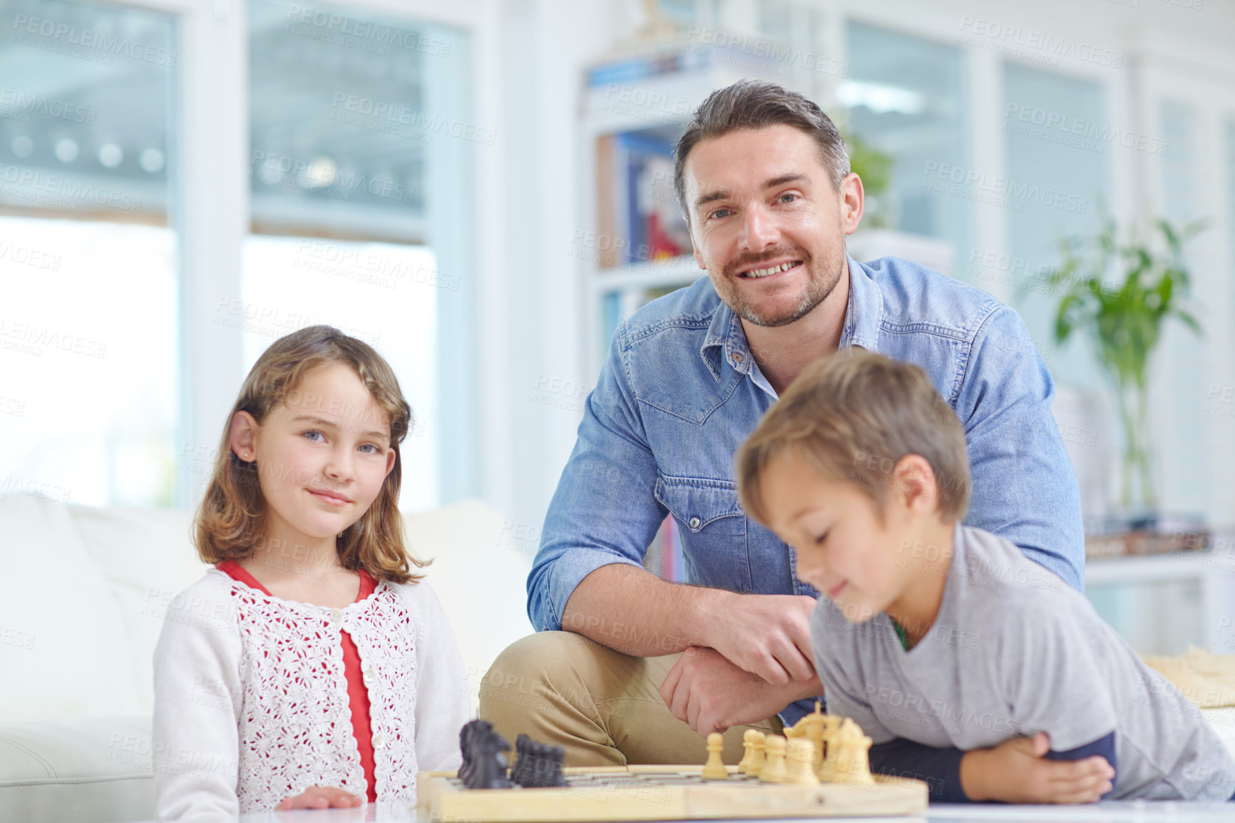 Buy stock photo Shot of a father playing a game of chess with his son and daughter at home