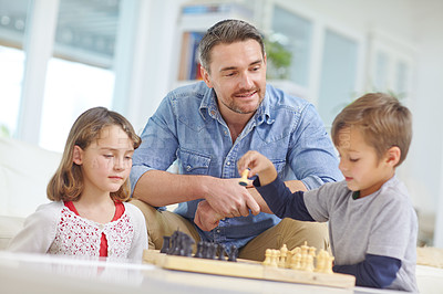 Buy stock photo Shot of a father playing a game of chess with his son and daughter at home