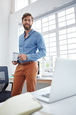 Buy stock photo Shot of a handsome designer holding a cup of coffee and a digital tablet