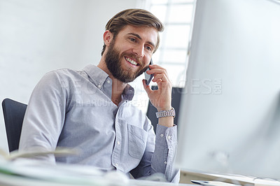 Buy stock photo Shot of a designer talking on his phone while reading something on his computer screen