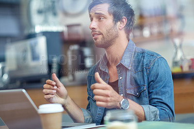 Buy stock photo Shot of a young man sitting in a coffee shop showing thumbs up to someone off-camera 