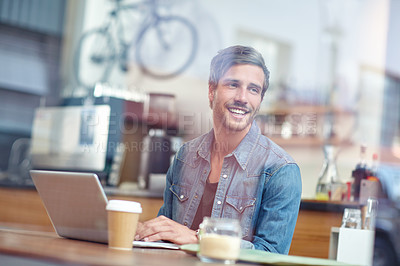 Buy stock photo Shot of a handsome young man sitting with his laptop in a coffee shop