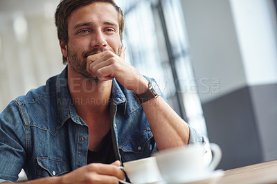 Buy stock photo Shot of a handsome young man looking thoughtful while having coffee at a cafe