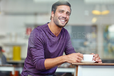 Buy stock photo Shot of a handsome young man enjoying a cup of coffee at a cafe