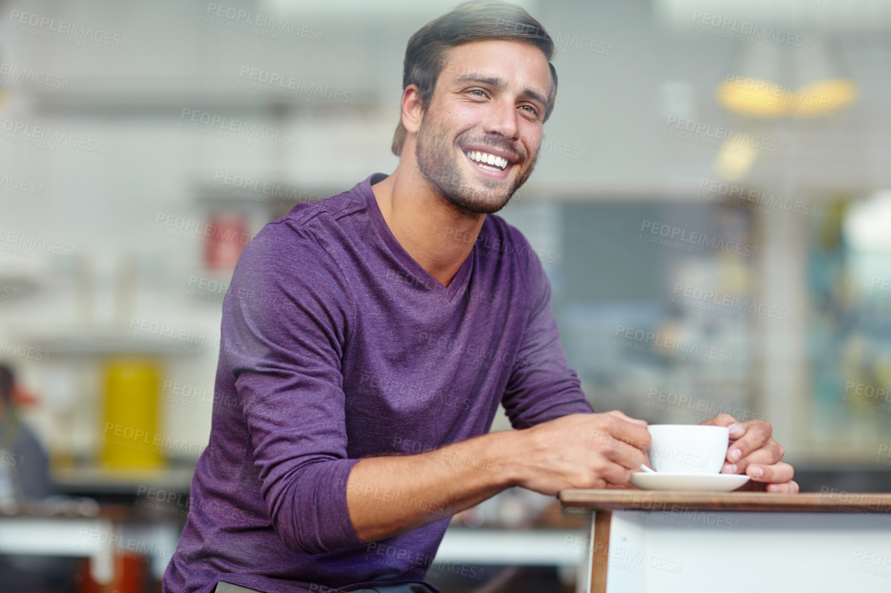 Buy stock photo Shot of a handsome young man enjoying a cup of coffee at a cafe