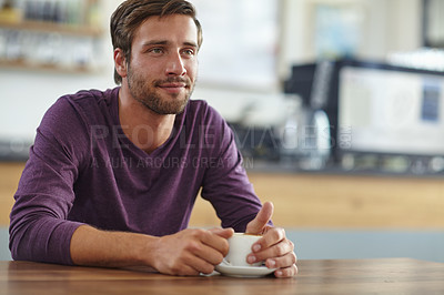 Buy stock photo Shot of a handsome young man looking thoughtful while drinking a cup of coffee at a cafe