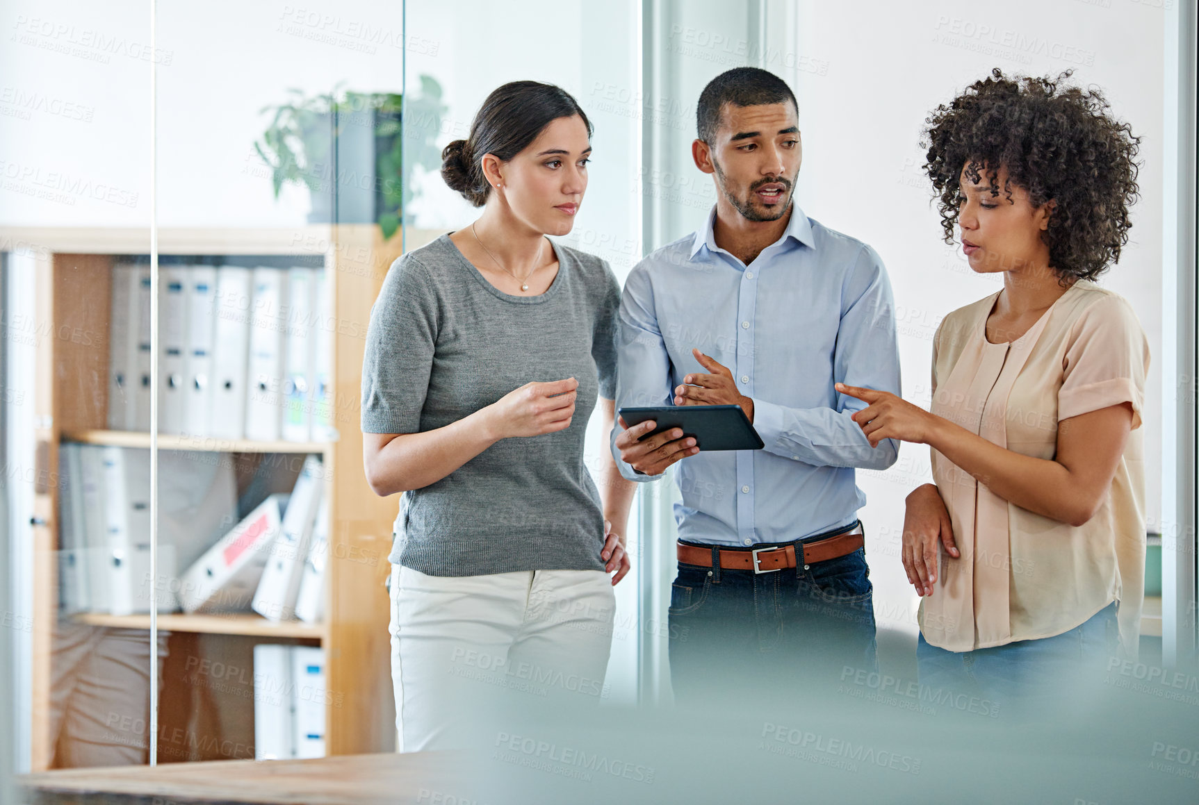 Buy stock photo Shot of office colleagues having a discussion over a digital tablet